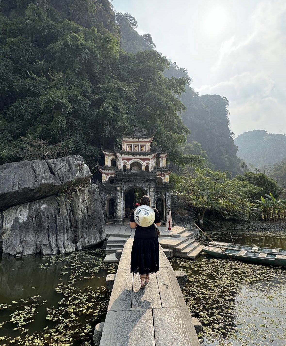 Local Vietnamese woman rowing a traditional sampan boat with her feet on the Ngo Dong River
